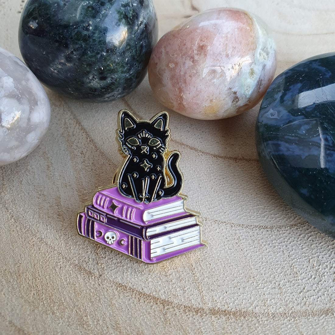 Enamel pin kat op stapel boeken